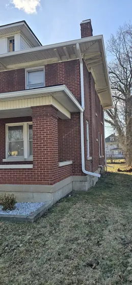 Brick house with crisp new white gutters and downspout